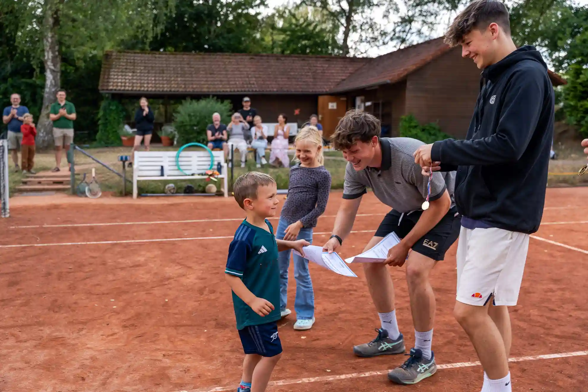 Trainer überreicht Urkunde an Jungen beim Tenniscamp 2025.