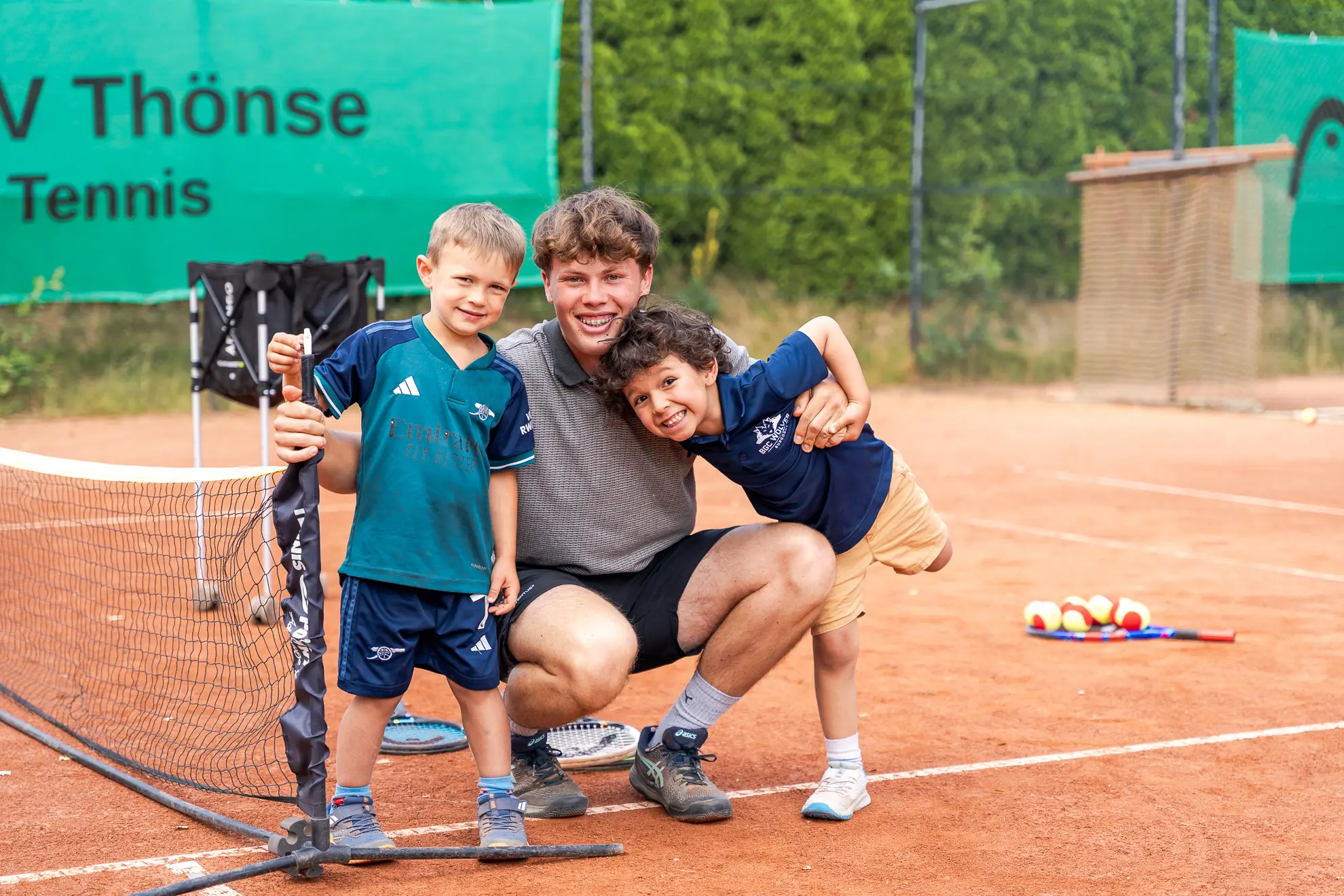Jan Garfert mit zwei Jungen auf dem Tennisplatz.